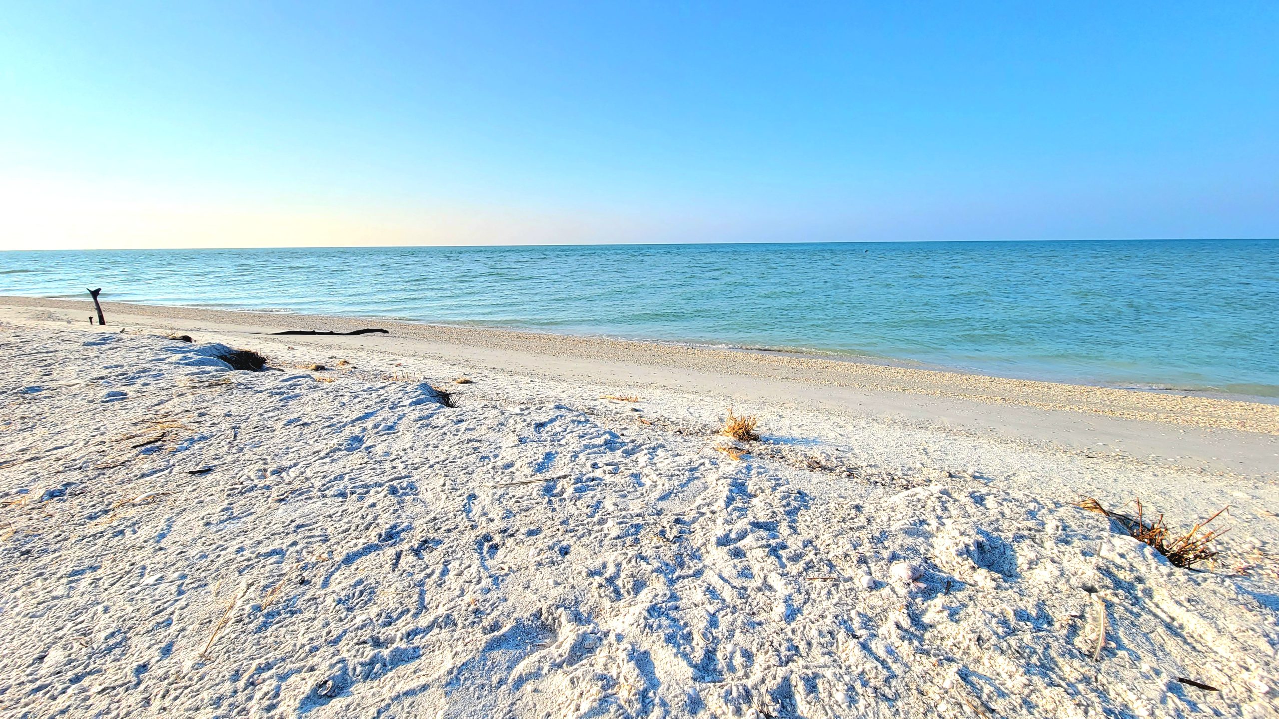 Sunny beach with white sand and calm blue sea.