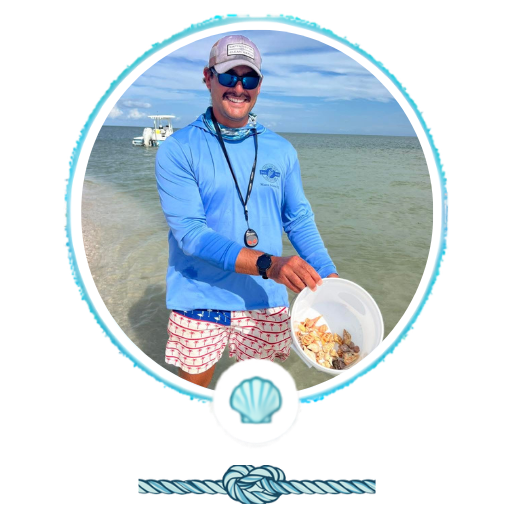 Person holding a bucket of shells on a beach with calm sea and boat in the background.