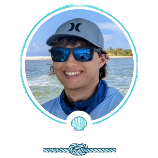 Person in sunglasses and hat smiling by the water.