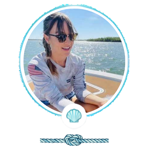 Person wearing sunglasses on a boat with water in the background.