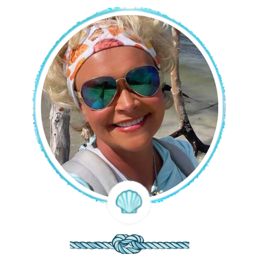 Person smiling with sunglasses, headband, and ocean backdrop.