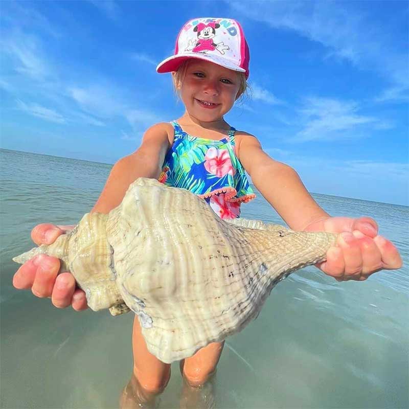 A little girl holding a shell she has just found.