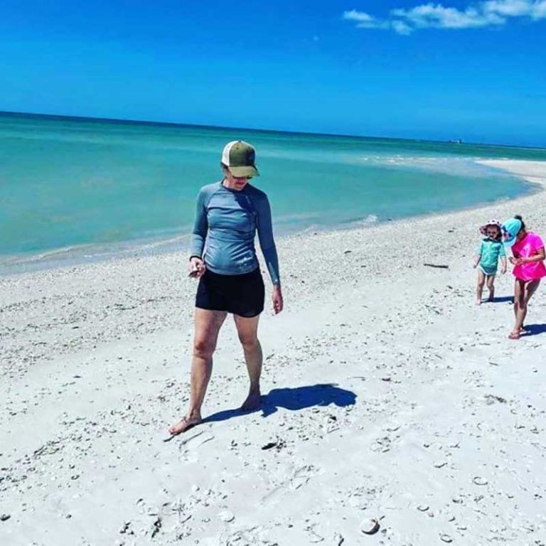 A woman and her children walking on the beach.
