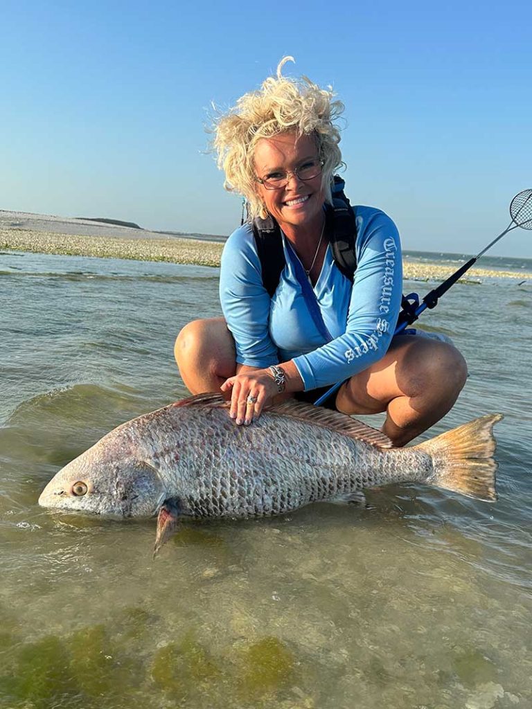 A woman who has caught a big fish during a fishing tour.