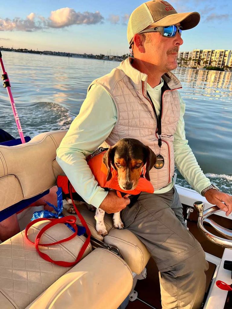 A man and his dog navigating a boat during a tour.