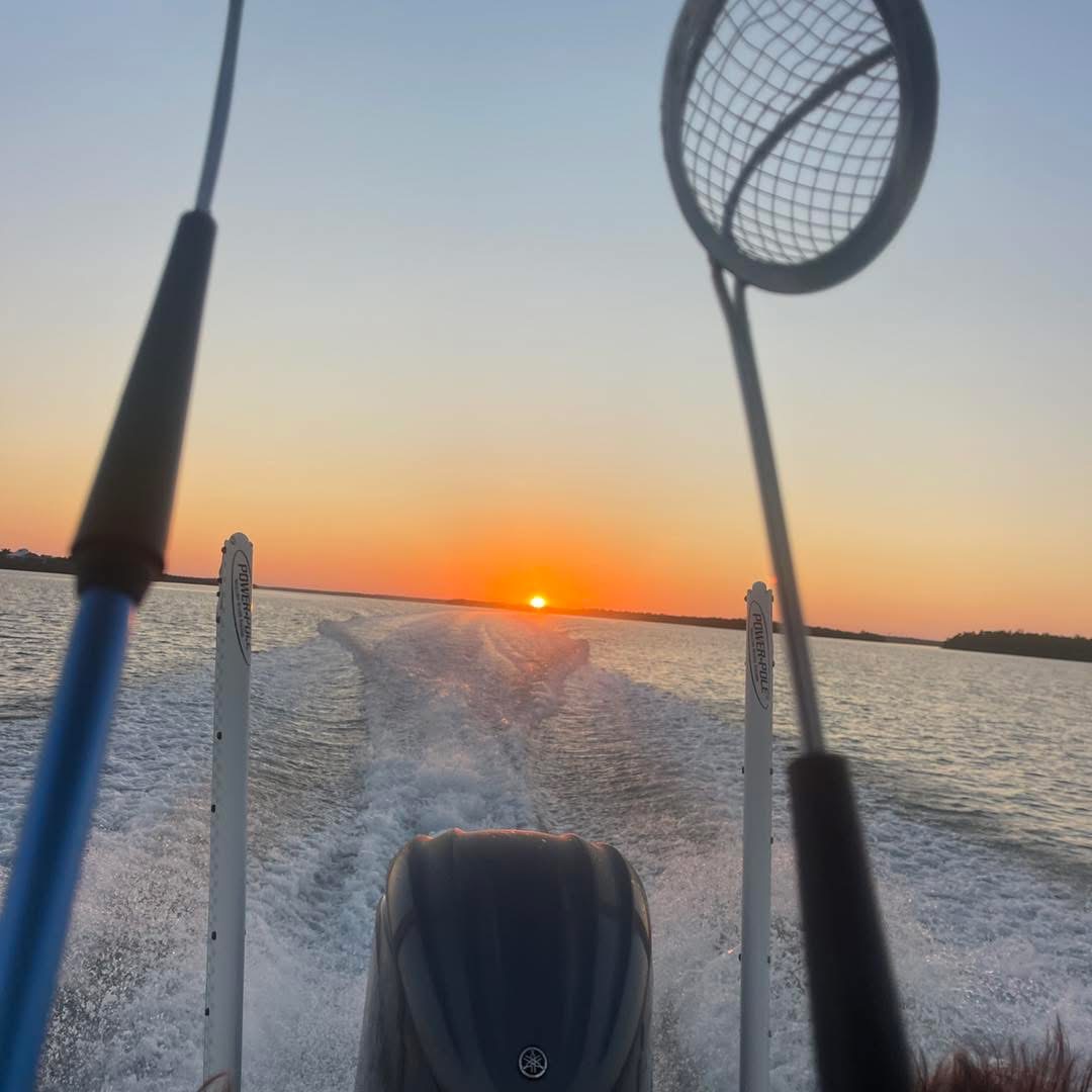 Sunset view from a boat with fishing net in the foreground.