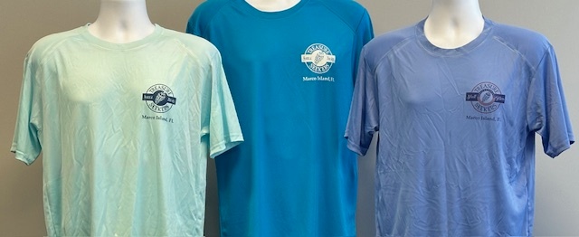 Three mannequins wearing teal, blue, and light blue shirts with logo.