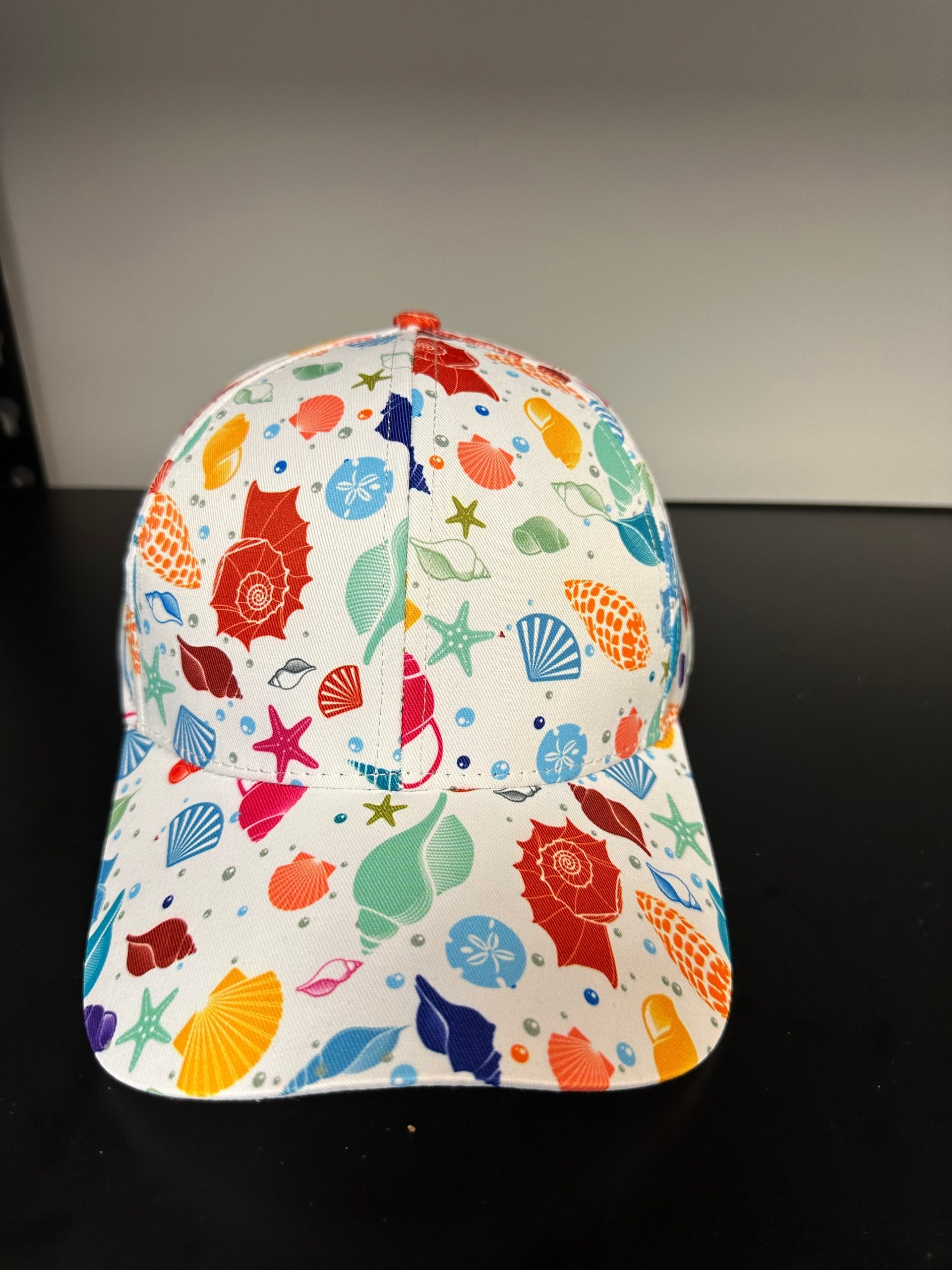 Colorful seashell-patterned cap on a black surface.