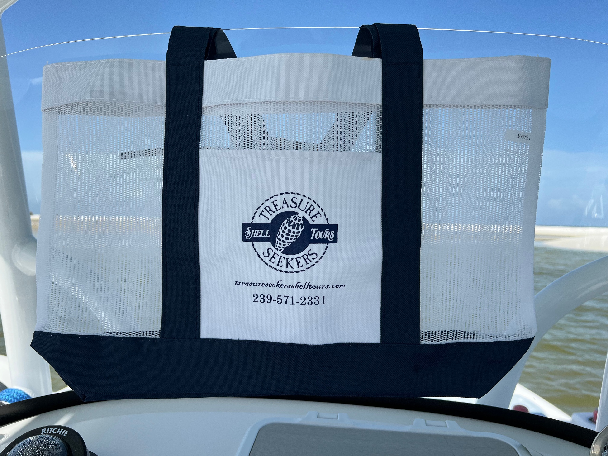 Mesh beach bag with 'Treasure Seekers' logo on a boat dashboard.