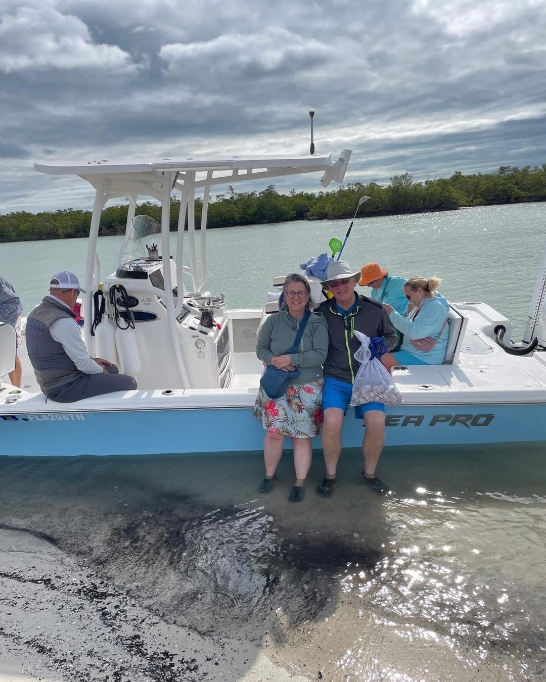People sitting on a boat by the shore under cloudy sky.
