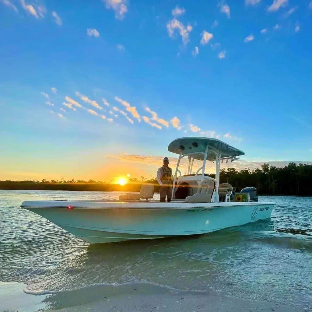 Boat on beach at sunrise with person onboard and clear sky.